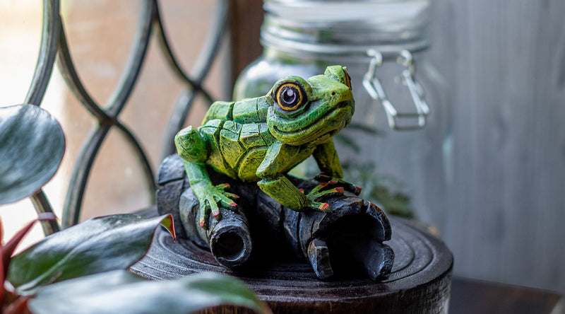 Green frog figurine on a wooden log with a blurred background