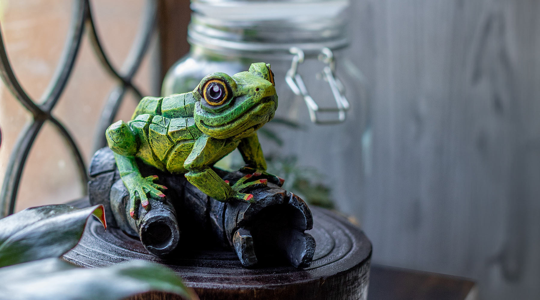 Green frog figurine on a wooden base with a blurred background
