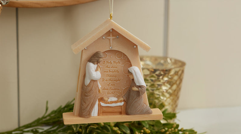 Decorative nativity scene ornament with Mary and Joseph holding baby Jesus, set against a neutral background.